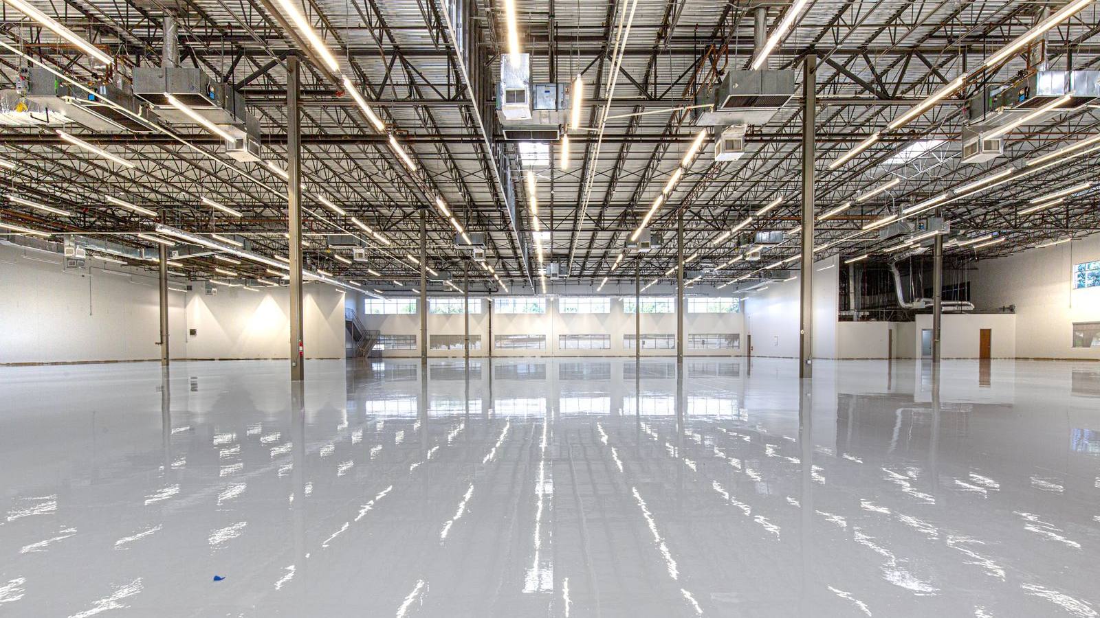 Wide, glossy epoxy-coated warehouse floor reflecting overhead lights
